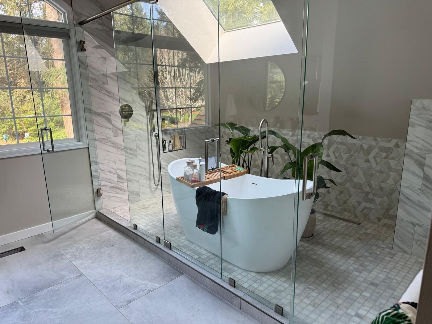 Frameless glass shower enclosure with skylight and freestanding tub